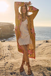 Woman in a long, patterned cardigan over a white dress standing on a rocky beach with ocean and sunset in the background.
Coastal Granny Maxi Cardigan