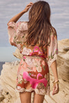 Woman wearing a floral kimono-style outfit with flamingo design on a rocky beach.
Floridian Lace Mini Dress