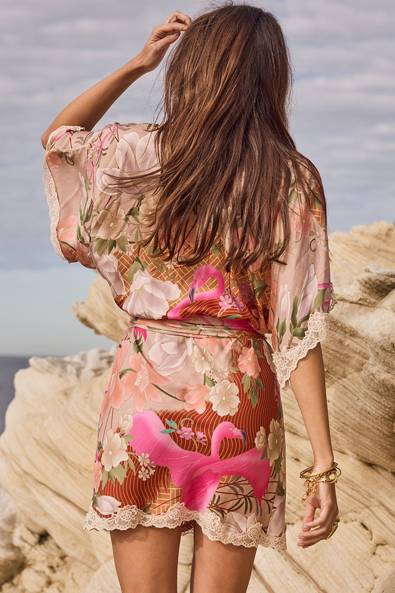 Woman wearing a floral kimono-style outfit with flamingo design on a rocky beach.
Floridian Lace Mini Dress