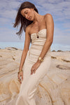 Woman in a strapless beige dress standing on a rocky beach with a blue sky.
Playa Midi Dress