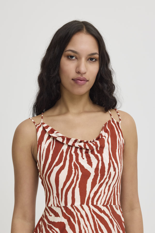 ICHI - Yardeen Dress
dress, long dress, maxi dress, midi dress, zebra print, zebra print dress, strappy dress, summer dress, spring dress, resort wear, holiday wear, resort dress

image shows model wearing a long dress with a rust coloured zebra print. it has a strappy open back and she is looking over her shoulder at the camera